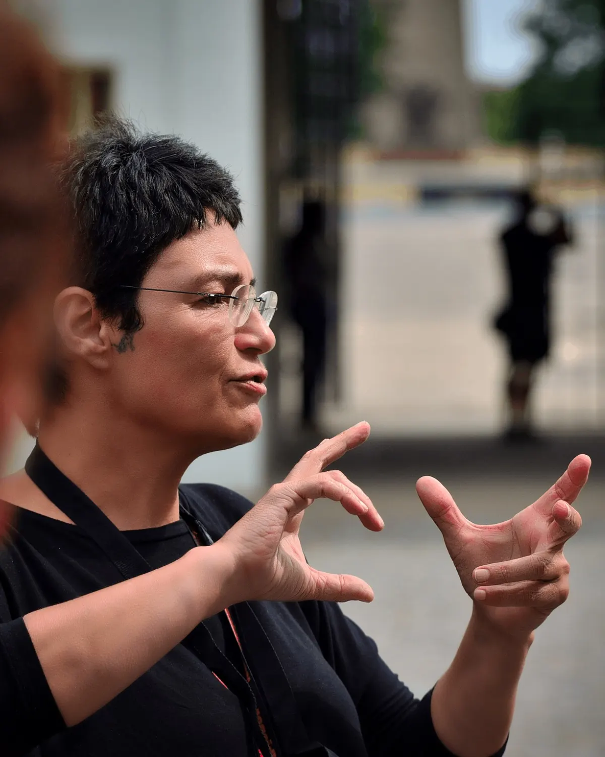 Marta falando e gesticulando durante uma explicação, em close